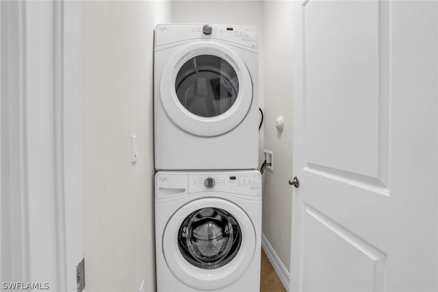 washroom with stacked washer and dryer and tile patterned flooring