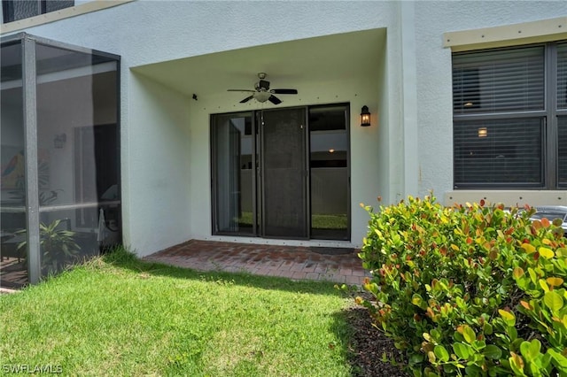 entrance to property featuring ceiling fan and a lawn