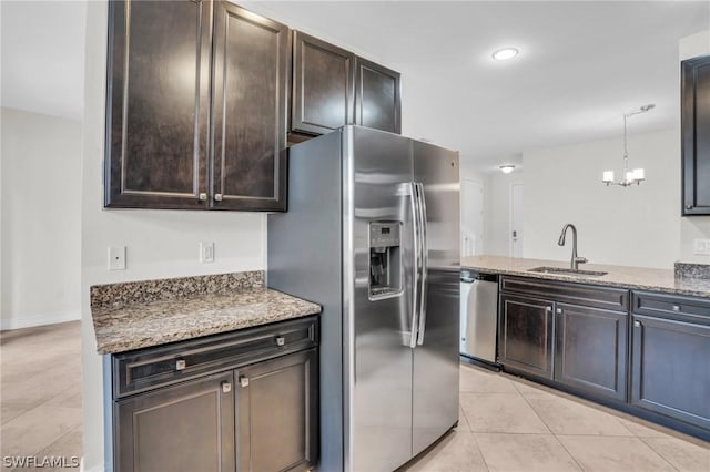 kitchen with sink, appliances with stainless steel finishes, hanging light fixtures, stone countertops, and light tile patterned flooring