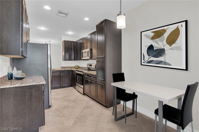 kitchen with pendant lighting, appliances with stainless steel finishes, light stone countertops, and dark brown cabinets