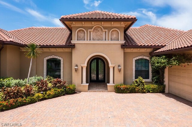 20180 Riverbrooke Run, Estero, FL 33928 - view of front of home featuring french doors, decorative driveway, a garage, stucco siding, and a tile roof