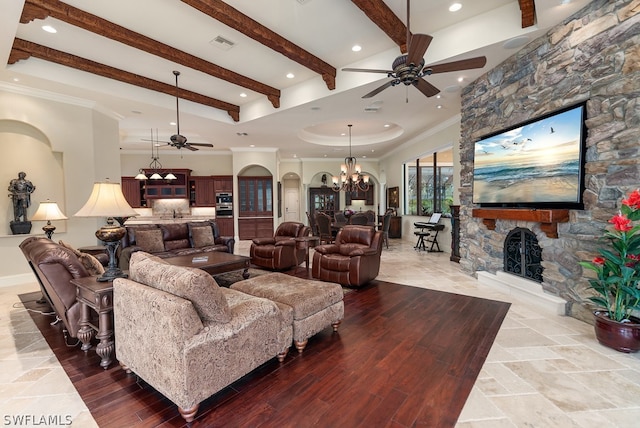 living room featuring hardwood / wood-style flooring, ornamental molding, beam ceiling, a fireplace, and a notable chandelier