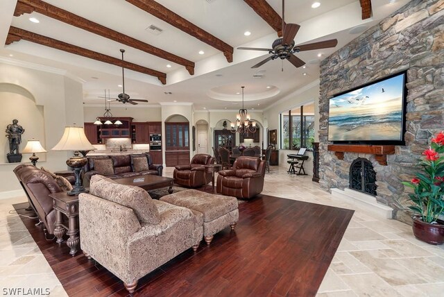 20180 Riverbrooke Run, Estero, FL 33928 - living room featuring a ceiling fan, a stone fireplace, a chandelier, beamed ceiling, and ornamental molding