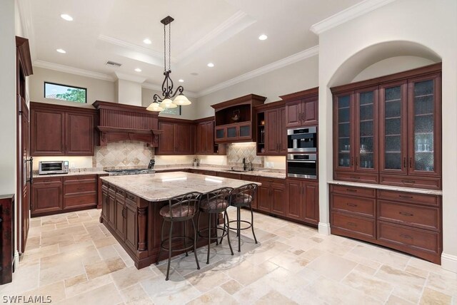 20180 Riverbrooke Run, Estero, FL 33928 - kitchen featuring a kitchen island, a breakfast bar, decorative backsplash, decorative light fixtures, and light stone counters