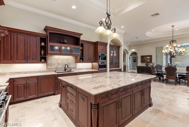 kitchen with decorative backsplash, hanging light fixtures, sink, and a center island