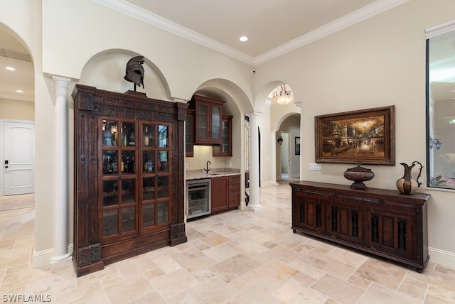 interior space with ornamental molding, wine cooler, sink, and decorative columns