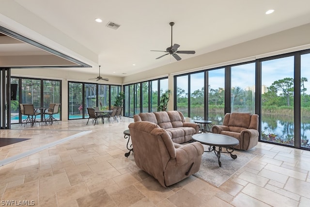 living room with a water view, ceiling fan, and crown molding