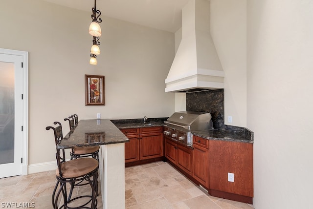 kitchen with sink, kitchen peninsula, custom range hood, a breakfast bar area, and hanging light fixtures