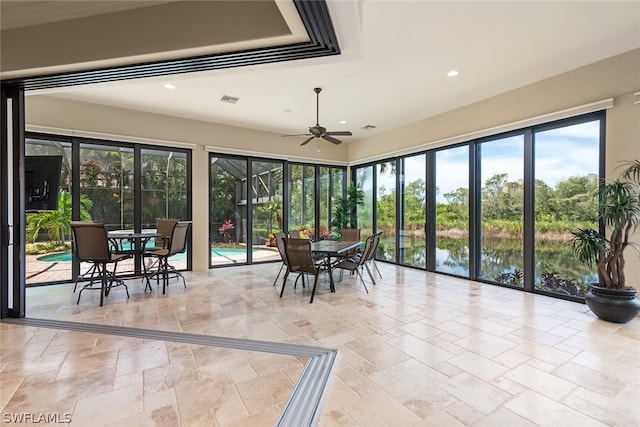 sunroom / solarium featuring ceiling fan and a water view