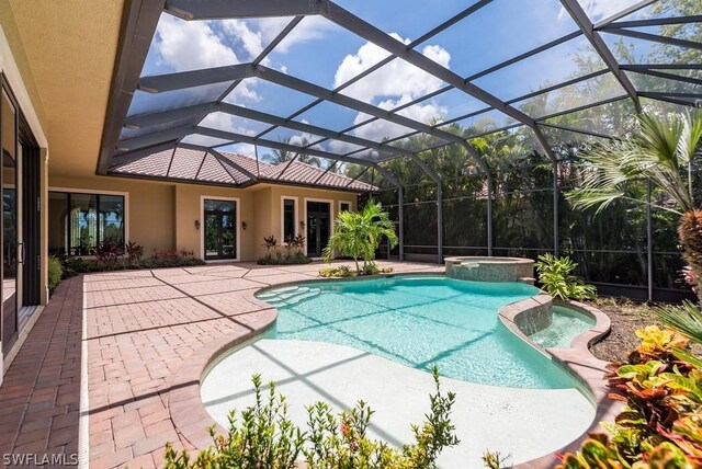 view of swimming pool with glass enclosure, an in ground hot tub, and a patio area