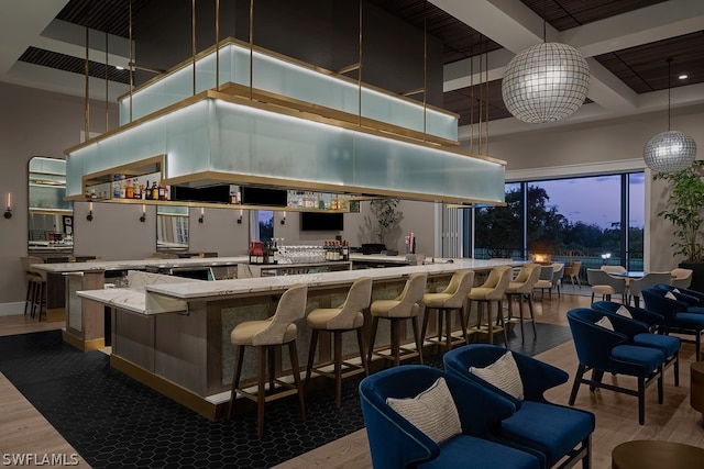 interior space with pendant lighting, a towering ceiling, hardwood / wood-style flooring, and beam ceiling