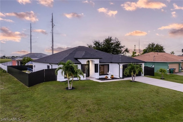 single story home featuring an attached garage, fence private yard, concrete driveway, and a yard