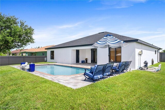 rear view of house with a patio, a fenced in pool, and a yard