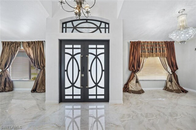 tiled entrance foyer featuring french doors, high vaulted ceiling, and a chandelier