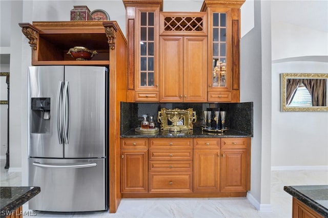 kitchen with dark stone counters, tasteful backsplash, stainless steel fridge, and light tile patterned floors