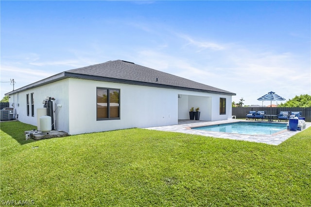 back of property with central AC, a fenced in pool, a lawn, and a patio area