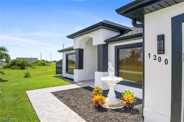 property entrance with a lawn and stucco siding