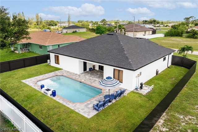 rear view of property featuring a yard, a fenced in pool, and a patio area