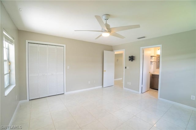 unfurnished bedroom featuring ensuite bath, light tile patterned floors, ceiling fan, and a closet