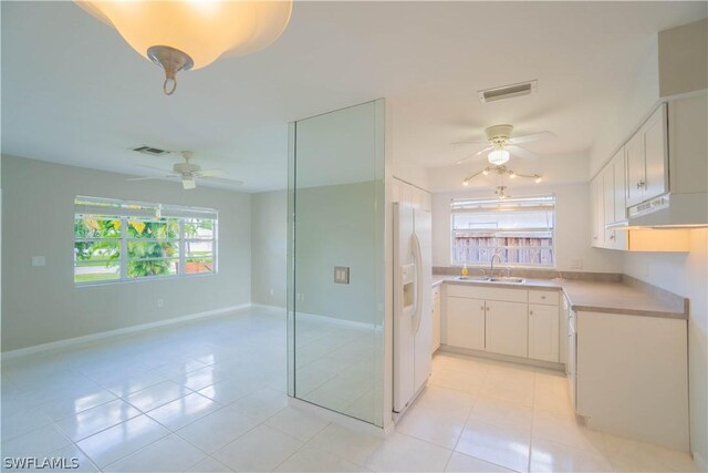 kitchen featuring sink, white cabinets, white fridge with ice dispenser, light tile patterned floors, and ceiling fan