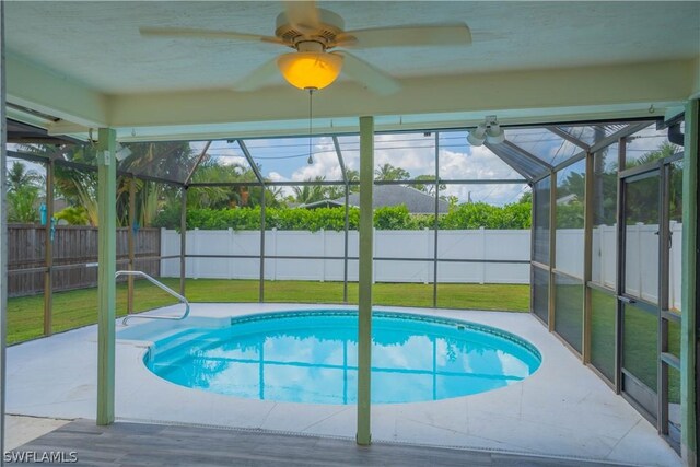 view of swimming pool with glass enclosure, a patio area, and a lawn