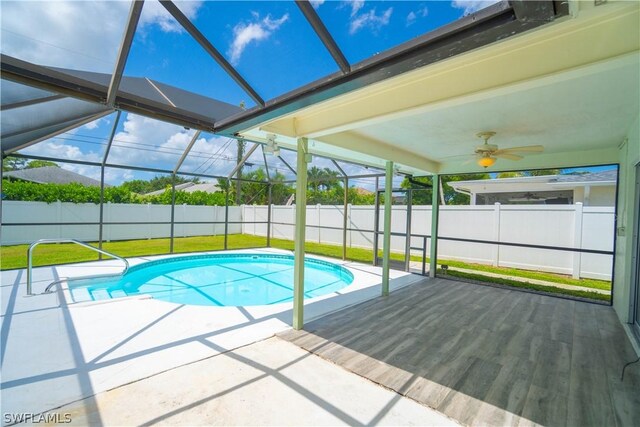 view of pool with ceiling fan, glass enclosure, and a patio