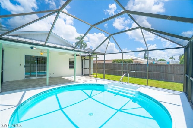 view of pool with ceiling fan, a patio area, glass enclosure, and a lawn