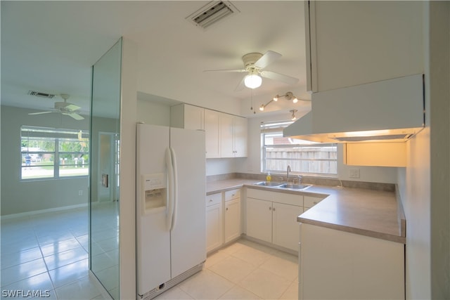 kitchen with sink, light tile patterned floors, white refrigerator with ice dispenser, and white cabinets