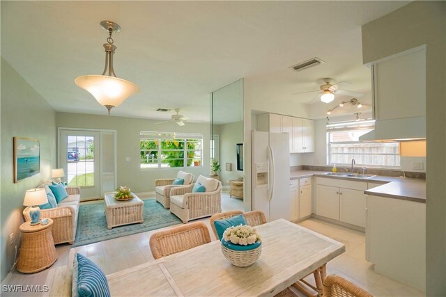 kitchen featuring white cabinetry, white refrigerator with ice dispenser, sink, and pendant lighting