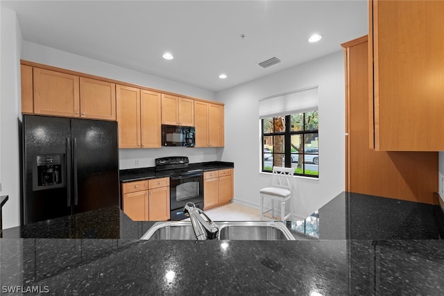 kitchen with sink, dark stone countertops, and black appliances