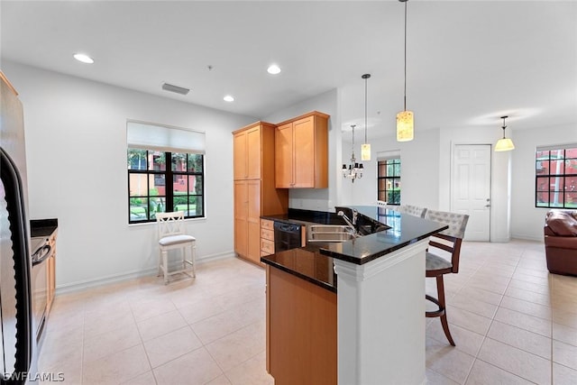 kitchen featuring a peninsula, a breakfast bar, a sink, visible vents, and pendant lighting