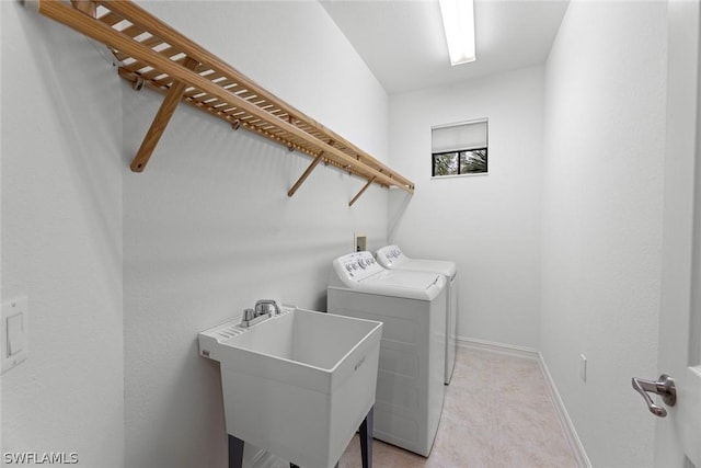 washroom with laundry area, separate washer and dryer, a sink, and baseboards