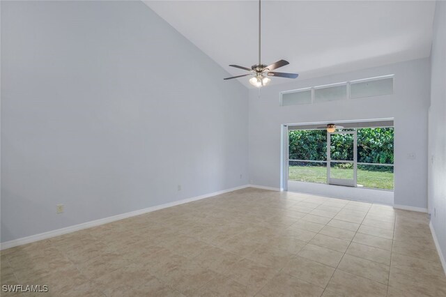 tiled empty room with ceiling fan and high vaulted ceiling