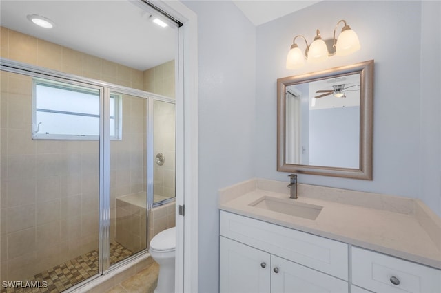 bathroom featuring tile patterned floors, a shower with shower door, vanity, ceiling fan, and toilet