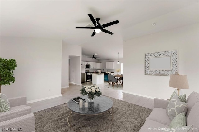 living room with ceiling fan, light hardwood / wood-style flooring, and vaulted ceiling