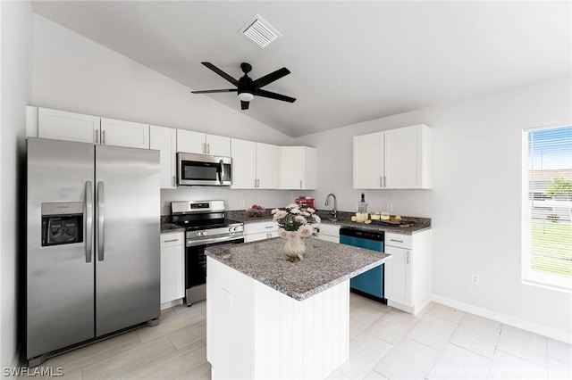 kitchen featuring white cabinetry, appliances with stainless steel finishes, a center island, and vaulted ceiling