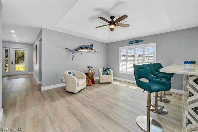 interior space with light wood-style floors, baseboards, and a tray ceiling