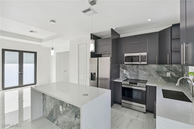 kitchen with light stone countertops, sink, stainless steel appliances, backsplash, and decorative light fixtures