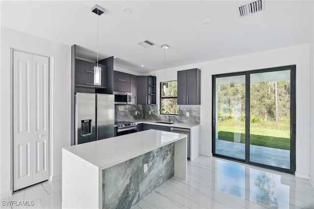 kitchen featuring sink, hanging light fixtures, stainless steel appliances, tasteful backsplash, and a kitchen island