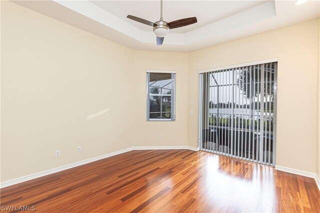 spare room featuring ceiling fan, a tray ceiling, and wood-type flooring