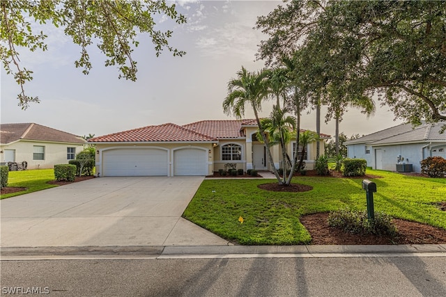 view of front of house featuring a garage, cooling unit, and a front yard