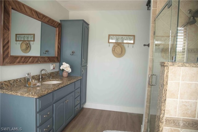 full bath with baseboards, vanity, wood finished floors, and a shower stall