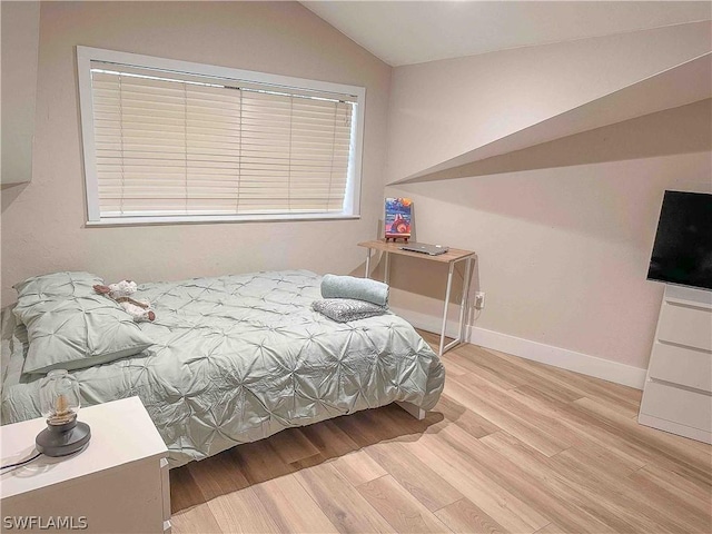 bedroom featuring wood finished floors, baseboards, and vaulted ceiling