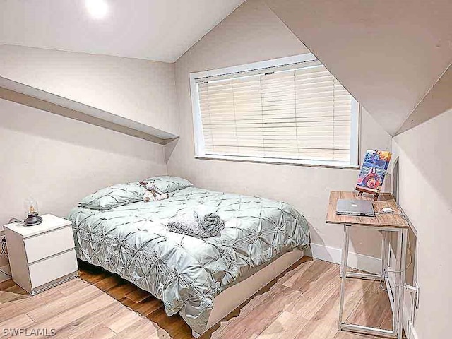 bedroom with baseboards, lofted ceiling, and light wood-style floors