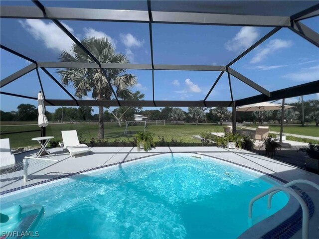 view of swimming pool featuring glass enclosure, a patio area, and a yard