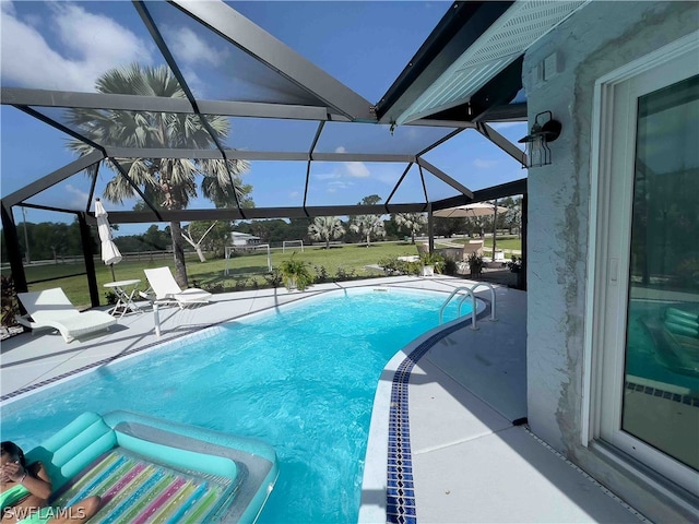 view of pool featuring glass enclosure, a yard, and a patio