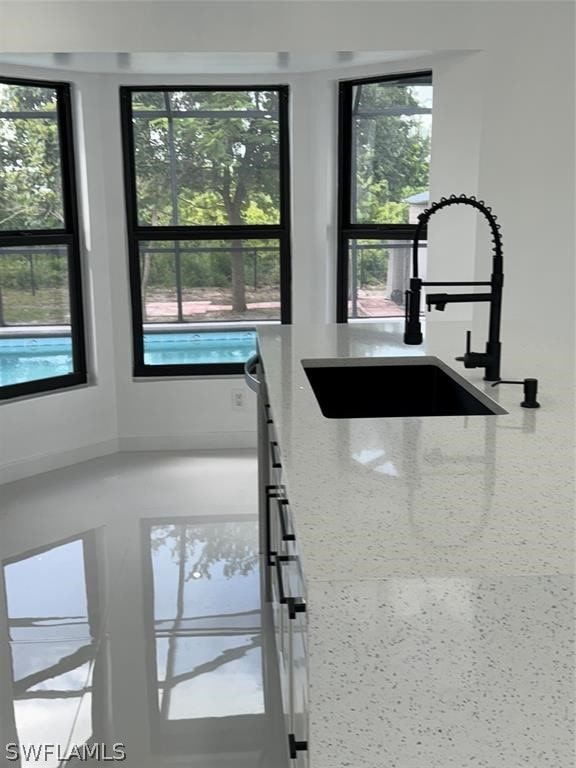 interior space featuring sink, light stone counters, and a healthy amount of sunlight