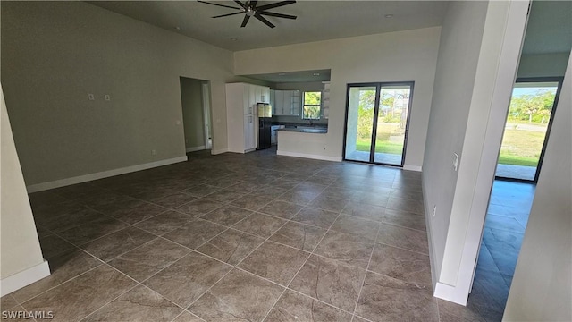 unfurnished living room featuring dark tile patterned flooring and ceiling fan