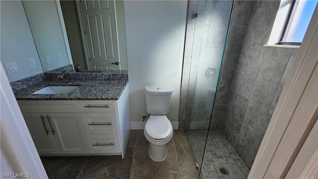 bathroom featuring a shower with door, vanity, and toilet