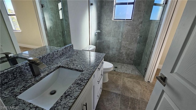 bathroom featuring toilet, plenty of natural light, vanity, and walk in shower